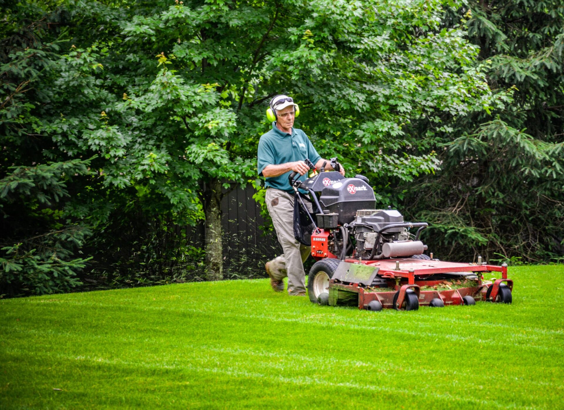 A team member mowing a client's lawn to help out with seasonal landscape maintenance in the summer.